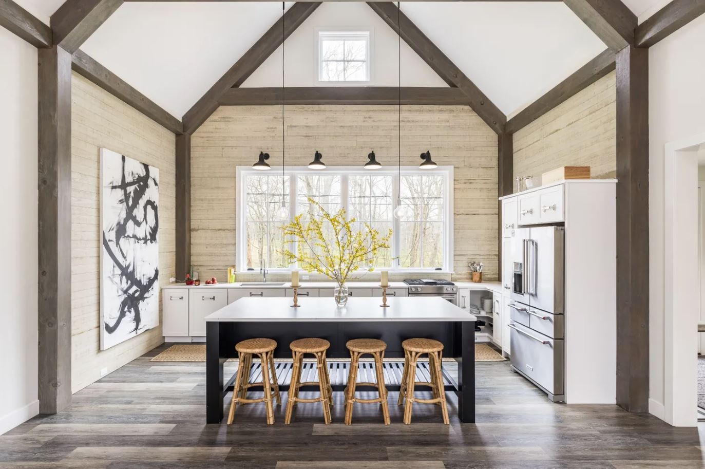 Moody Kitchen with white shaker cabinets and a custom black furniture island with exposed wood beams and giant windows.